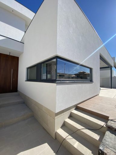 Esquina de una casa moderna con ventanal y escaleras de acceso.