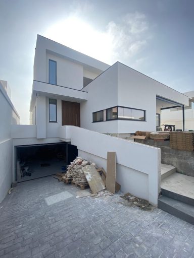 Casa moderna de dos pisos con un diseño minimalista y un camino de acceso en construcción.